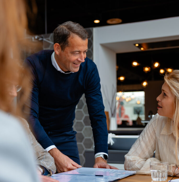 Collega staat naast tafel en heeft overleg